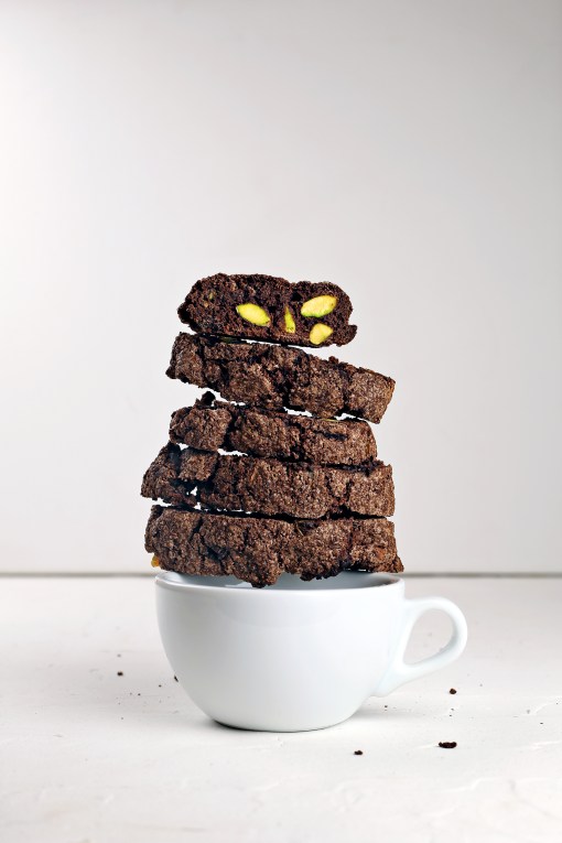 Double chocolate & pistachio biscotti perched on a coffee cup